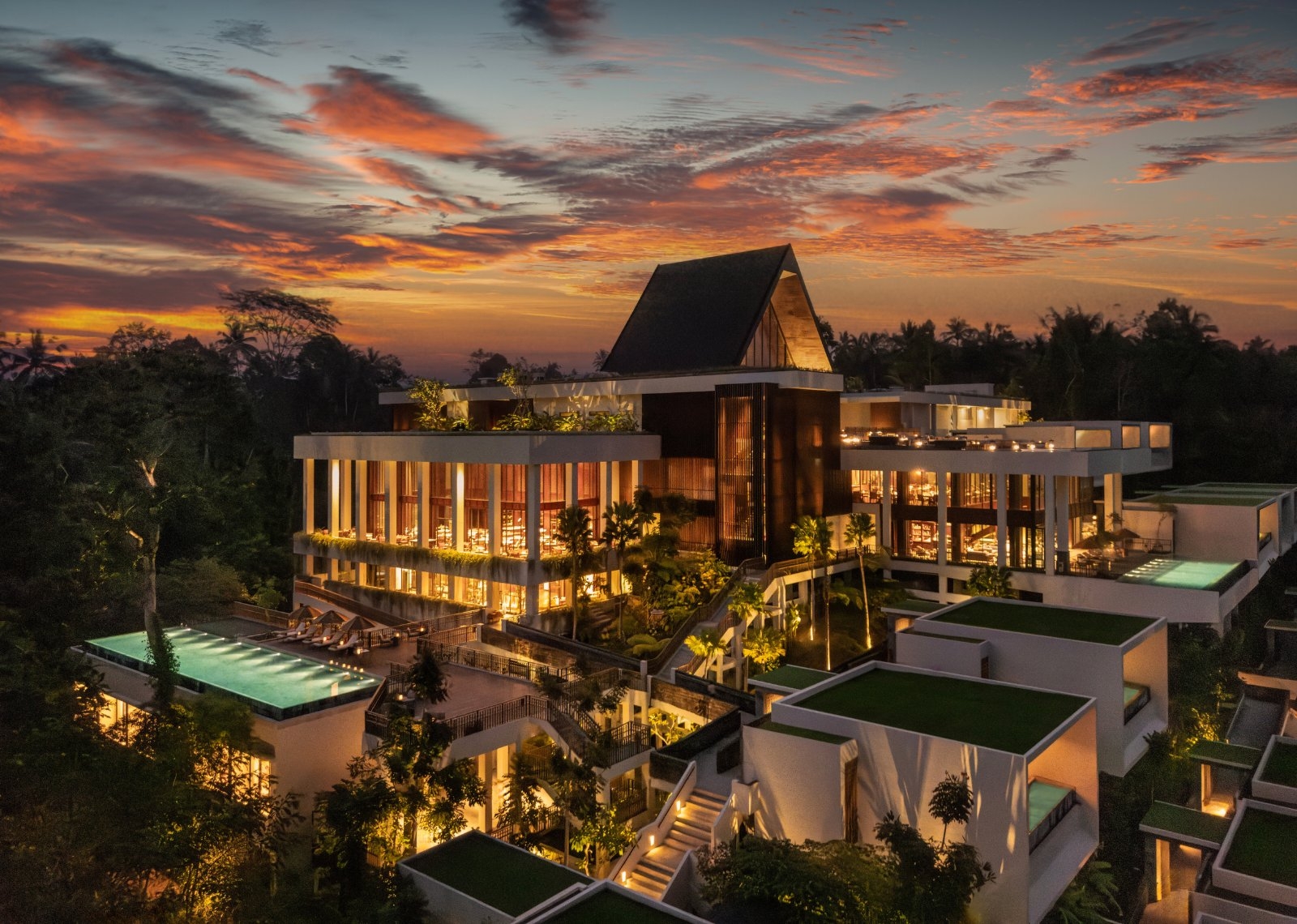 Captured from above at sunset, Anantara Ubud Bali Resort emerges from a landscape of lush forests and rolling hills, bathed in the warm glow of dusk.