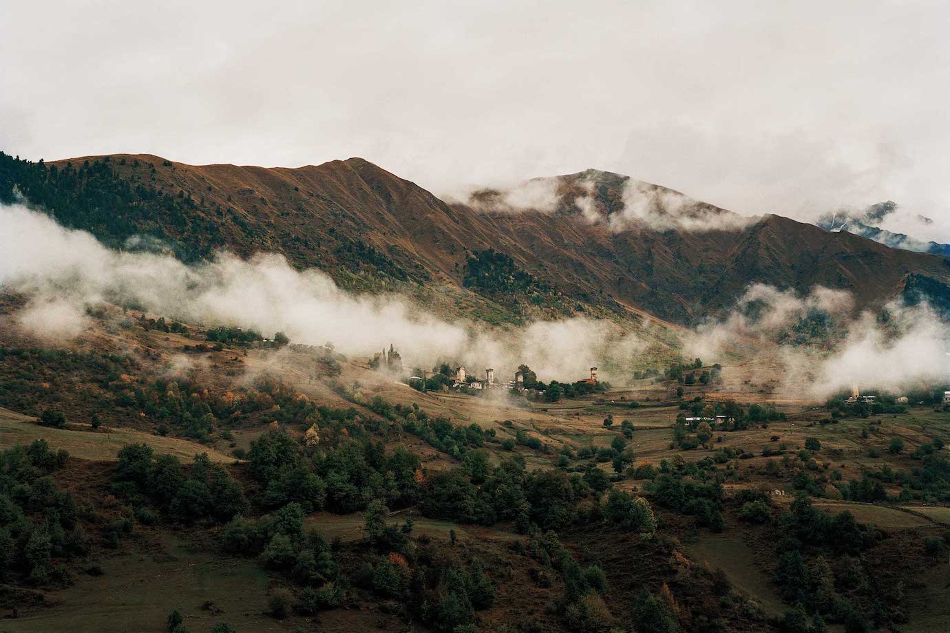 Morning fog rising from a medieval mountain village in the Svaneti region of northern Georgia.