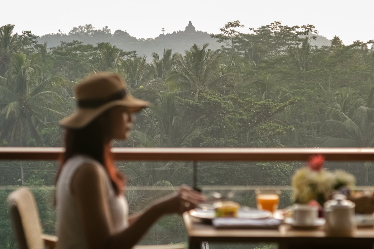 A guest at Plataran Borobudur enjoys an outdoor breakfast with a view of Borobudur temple.