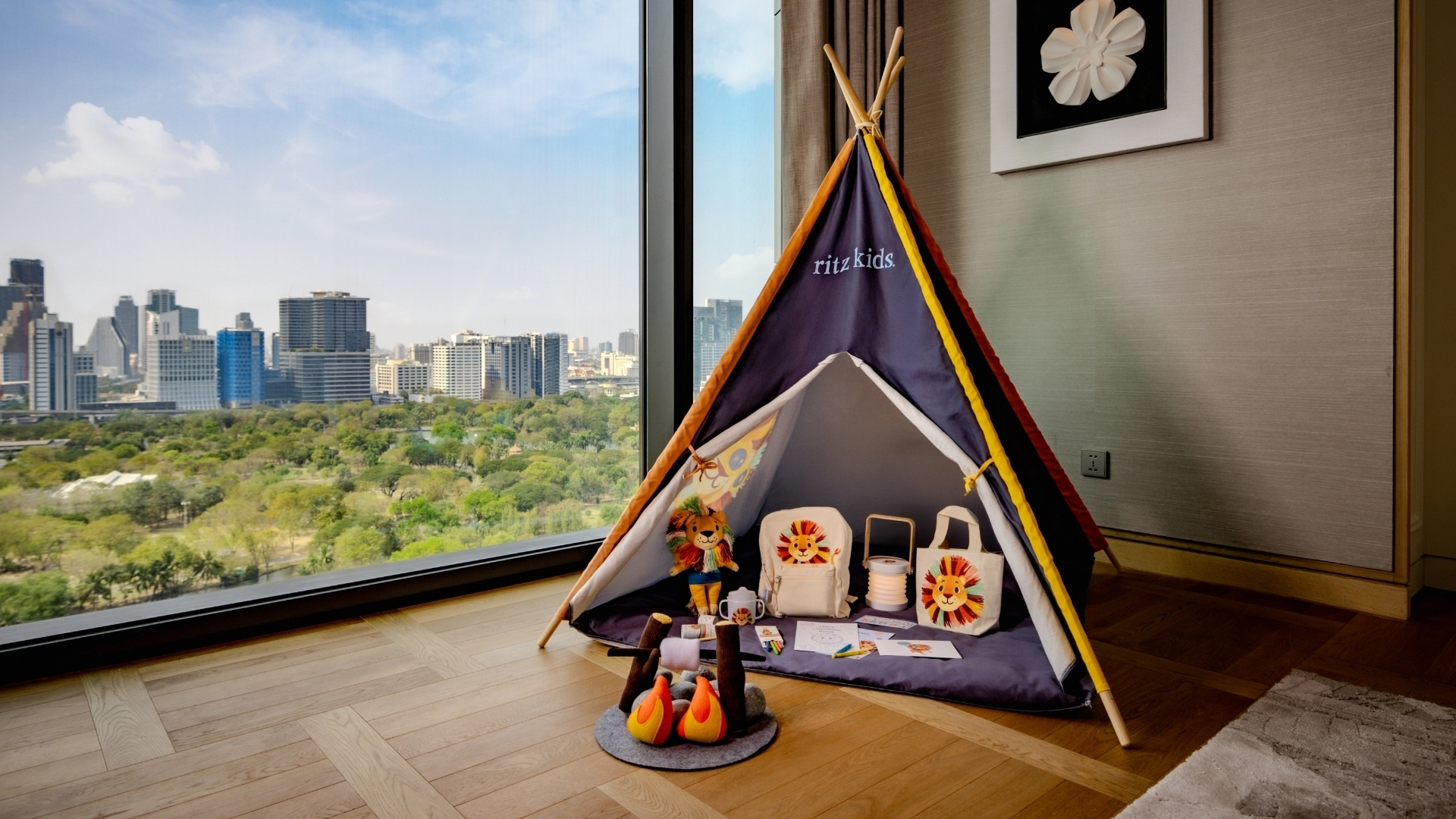 Ritz Kids indoor play tent set up next to a large floor-to-ceiling window overlooking a park in a luxury family suite at The Ritz-Carlton, Bangkok.