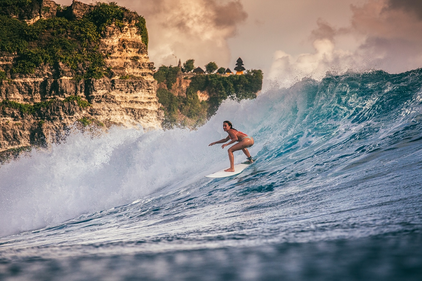 Catching a wave at Bali’s iconic Uluwatu surf break.
